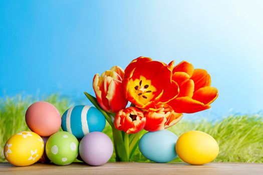 Easter eggs with tulips on spring grass background