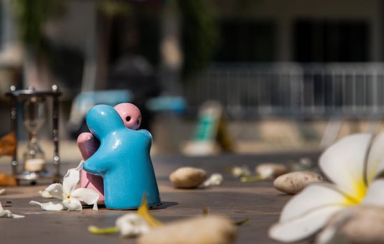 Blue and pink ceramic couple dolls hug with each other on stone background. Concept for anniversary, Wedding and eternal love concept, Romance wedding or Valentine’s day.