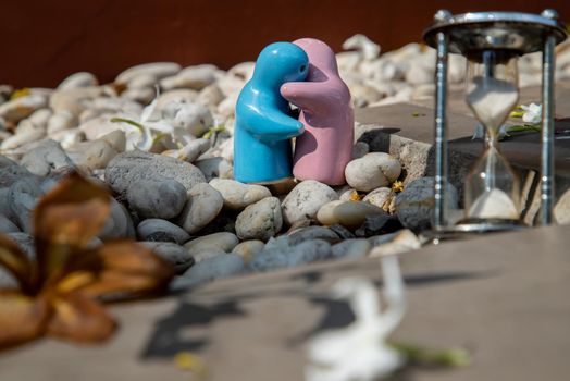 Blue and pink ceramic couple dolls hug with each other on stone background. Concept for anniversary, Wedding and eternal love concept, Romance wedding or Valentine’s day.