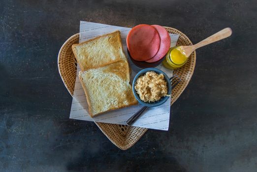 Traditional thai sandwich with slices of toast bread, Bologna sausage and Shredded pork, Homemade sweet mayonnaise in Wicker tray. Thai language written on Food parchment Translated into English as "Traditional sandwiches 2563" Sandwich thai style. No focus, specifically.