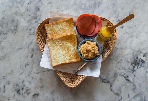 Traditional thai sandwich with slices of toast bread, Bologna sausage and Shredded pork, Homemade sweet mayonnaise in Wicker tray. Thai language written on Food parchment Translated into English as "Traditional sandwiches 2563" Sandwich thai style. No focus, specifically.