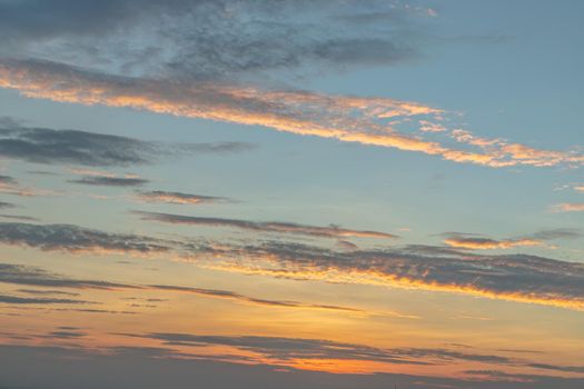 Scenic Colorful Sky At Sunset. Light blue clouds and orange on background, The softness of the cloud creates a feeling of relaxation. Copy space. No focus, specifically.
