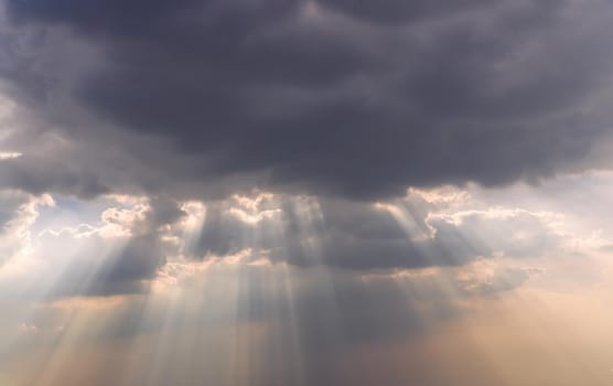 The sun's rays passing through the clouds and shining form an interesting light pattern against the sky. Copy space. Selective focus.