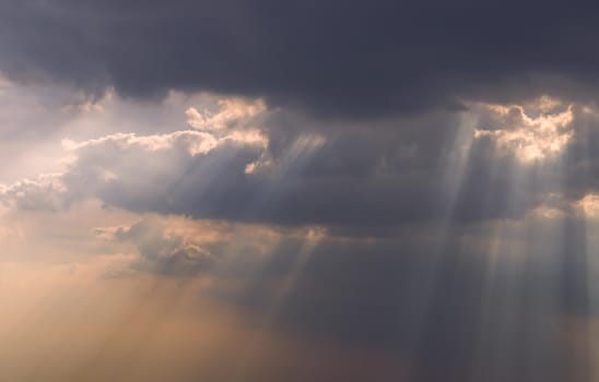 The sun's rays passing through the clouds and shining form an interesting light pattern against the sky. Copy space. Selective focus.
