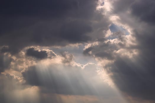 The sun's rays passing through the clouds and shining form an interesting light pattern against the sky. Copy space. Selective focus.