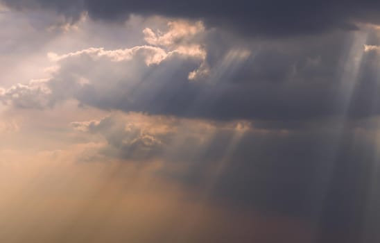 The sun's rays passing through the clouds and shining form an interesting light pattern against the sky. Copy space. Selective focus.