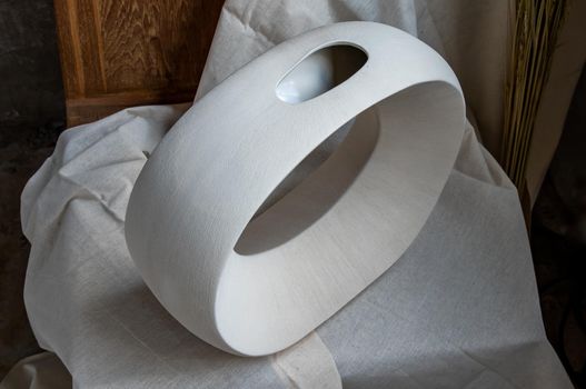 Beautiful ceramic white vase handmade on wooden chair. Home decor, Space for text.