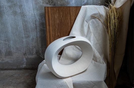 Beautiful ceramic white vase handmade on wooden chair. Home decor, Space for text.