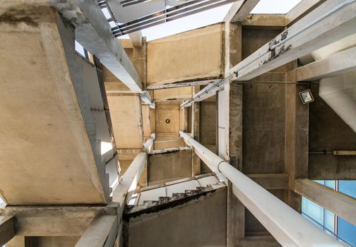 Looking up at Emergency fire escape staircase on the back side of a high concrete building. Fire safety. The geometry of the building, No focus, specifically.