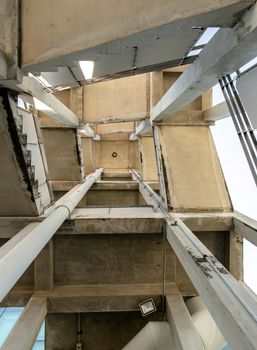 Looking up at Emergency fire escape staircase on the back side of a high concrete building. Fire safety. The geometry of the building, No focus, specifically.