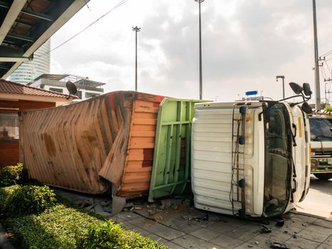 A truck carrying a container overturned on a road under a bridge over an intersection.