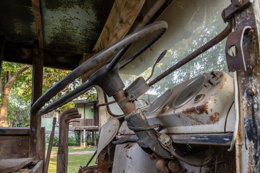 A rusty Old log truck cabin with Car steering wheel. Abandoned car, select focus.