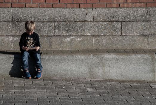 Liverpool, United Kingdom - 03 Jan 2019 : Child sitting on the aisle and watching something on Ipod in the aisle at River Mersey, Royal Albert Dock. Copy space, Focus and blur.