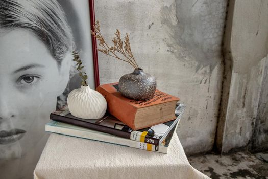 Dried flowers in Handmade Double ceramic Vases and books on table. Home decor, Space for text.
