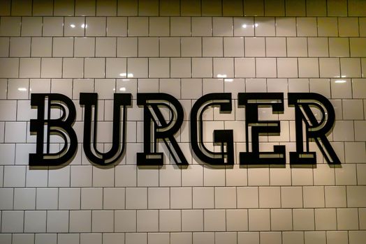 Burgers lettering signage in black letters on the Ceramic tile floor wall background. Simple symbol and modern sign for fast food, Burger logo, Burger Sign, Burger Concept, Text and word, No focus, specifically.