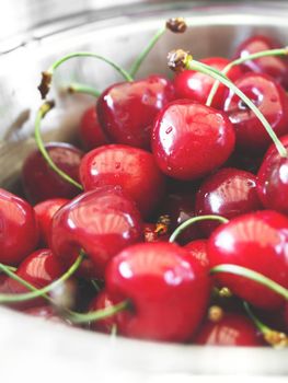 Close - up of ripe and juicy red cherries in a glass bowl.