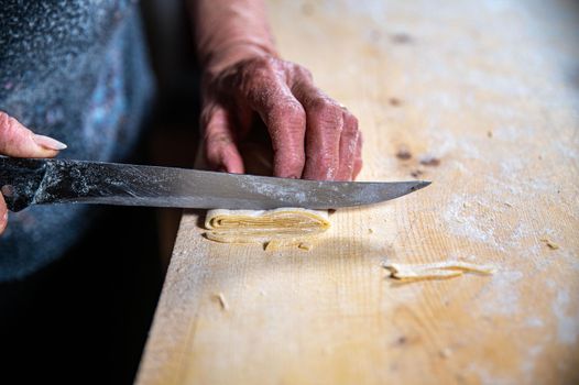 the grandmother prepares homemade egg pasta noodles