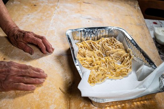 grandma arranges egg noodles on the aluminum insole