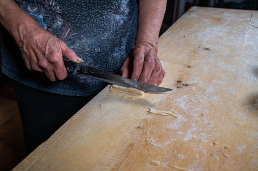 the grandmother prepares homemade egg pasta noodles
