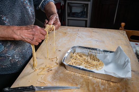 grandma arranges egg noodles on the aluminum insole