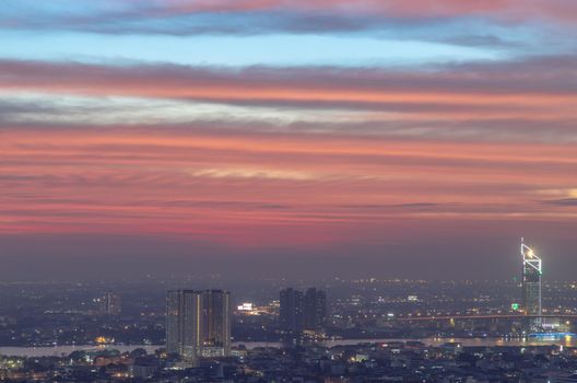 Bangkok, thailand - Dec 23, 2020 : Aerial view of Bangkok city Overlooking Skyscrapers and the Bridge crosses the Chao Phraya river with bright glowing lights at dusk. No focus, specifically.