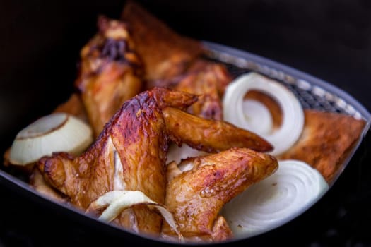 Close-up of Baked pickled chicken wings and Onion. Cooking chicken with spices puts on slice of bread in the Hot air oven. Selective focus.