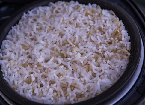 Jasmine rice Cooking mixed with Coarse brown rice (milled rice imperfectly cleaned, unpolished or half milled rice) in electric rice cooker with steam. Healthy food and diet concept. Selective focus.
