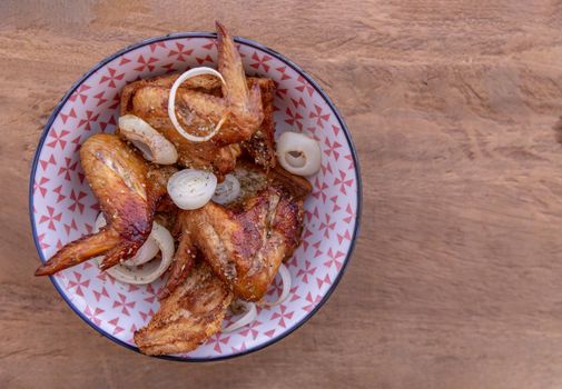 Baked pickled chicken wings with Spices and Onion in a japanese bowl on wooden background. Top view, Copy space, Selective focus.