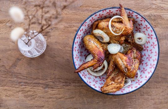 Baked pickled chicken wings with Spices and Onion in a japanese bowl on wooden background. Top view, Copy space, Selective focus.