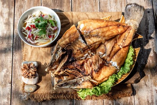 Deep fried Snapper with fish sauce on vintage wooden, The perfect frying process, Set hot fire, then bring the snapper to fry to frame and topped with fish sauce.
