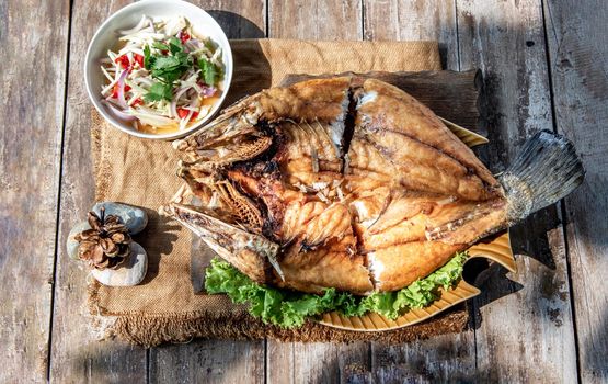 Deep fried Snapper with fish sauce on vintage wooden, The perfect frying process, Set hot fire, then bring the snapper to fry to frame and topped with fish sauce.