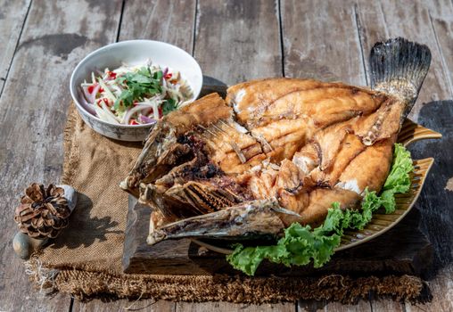 Deep fried Snapper with fish sauce on vintage wooden, The perfect frying process, Set hot fire, then bring the snapper to fry to frame and topped with fish sauce.