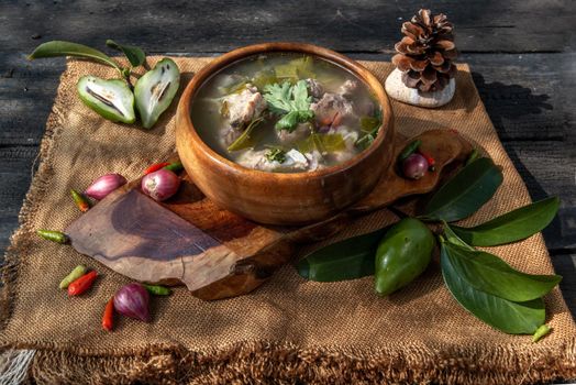Pork spare rip Madan soup (Kra Dook Moo Tom Ma-Dun) in a wooden bowl, Traditional Thai food, Oblique view from the top.