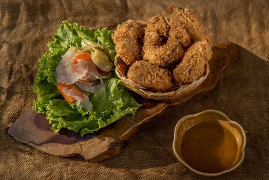 Deep-fried shrimp cakes (Tod Mun Goong) and vegetable with chili sauce on wooden background, Thai cuisine.