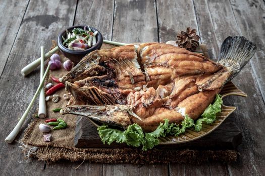 Deep fried Snapper with fish sauce on vintage wooden, The perfect frying process, Set hot fire, then bring the snapper to fry to frame and topped with fish sauce.