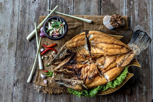 Deep fried Snapper with fish sauce on vintage wooden, The perfect frying process, Set hot fire, then bring the snapper to fry to frame and topped with fish sauce.