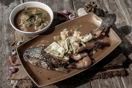 Deep fried whole Snakehad fish topped with Acacia omelets in vegetable sour soup (Orange curry with Cha-om).