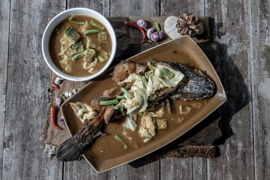 Deep fried whole Snakehad fish topped with Acacia omelets in vegetable sour soup (Orange curry with Cha-om).