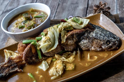 Deep fried whole Snakehad fish topped with Acacia omelets in vegetable sour soup (Orange curry with Cha-om).