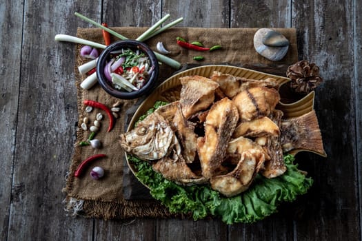 Deep fried Tubtim fish with fish sauce on vintage wooden, The perfect frying process, Set hot fire, then bring the Tubtim fish to fry to frame and topped with fish sauce.