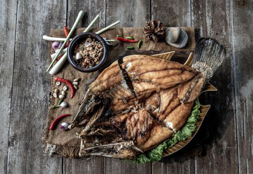 Deep fried Snapper with fish sauce on vintage wooden, The perfect frying process, Set hot fire, then bring the snapper to fry to frame and topped with fish sauce.