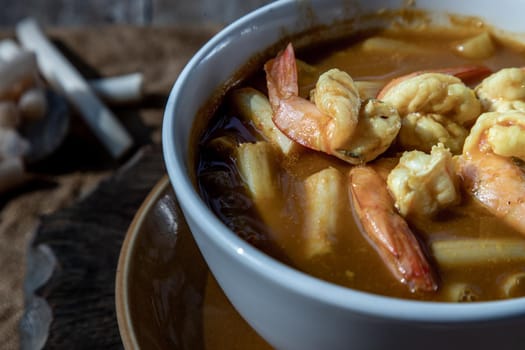 Close-up of Sour soup with lotus stem and shrimps (kaeng som koong with lotus stem), Traditional Thai food.