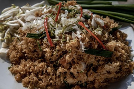 Asian eating food, Close-up of Mee Grob is an sweet and sour crispy noodles, made from Thai rice noodle with sweet and sour sauce on white plate, Sweet & Sour Crispy Rice Noodles.