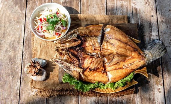 Deep fried Snapper with fish sauce on vintage wooden, The perfect frying process, Set hot fire, then bring the snapper to fry to frame and topped with fish sauce.