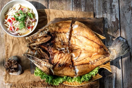 Deep fried Snapper with fish sauce on vintage wooden, The perfect frying process, Set hot fire, then bring the snapper to fry to frame and topped with fish sauce.