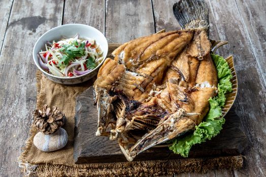 Deep fried Snapper with fish sauce on vintage wooden, The perfect frying process, Set hot fire, then bring the snapper to fry to frame and topped with fish sauce.