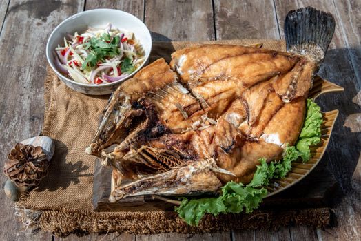 Deep fried Snapper with fish sauce on vintage wooden, The perfect frying process, Set hot fire, then bring the snapper to fry to frame and topped with fish sauce.