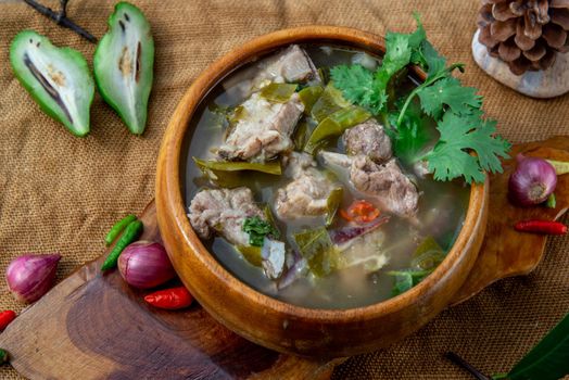 Pork spare rip Madan soup (Kra Dook Moo Tom Ma-Dun) in a wooden bowl, Traditional Thai food, Oblique view from the top.