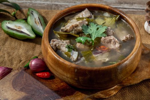 Pork spare rip Madan soup (Kra Dook Moo Tom Ma-Dun) in a wooden bowl, Traditional Thai food, Oblique view from the top.