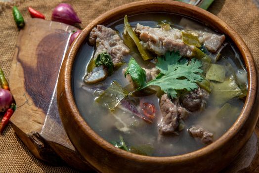 Pork spare rip Madan soup (Kra Dook Moo Tom Ma-Dun) in a wooden bowl, Traditional Thai food, Oblique view from the top.